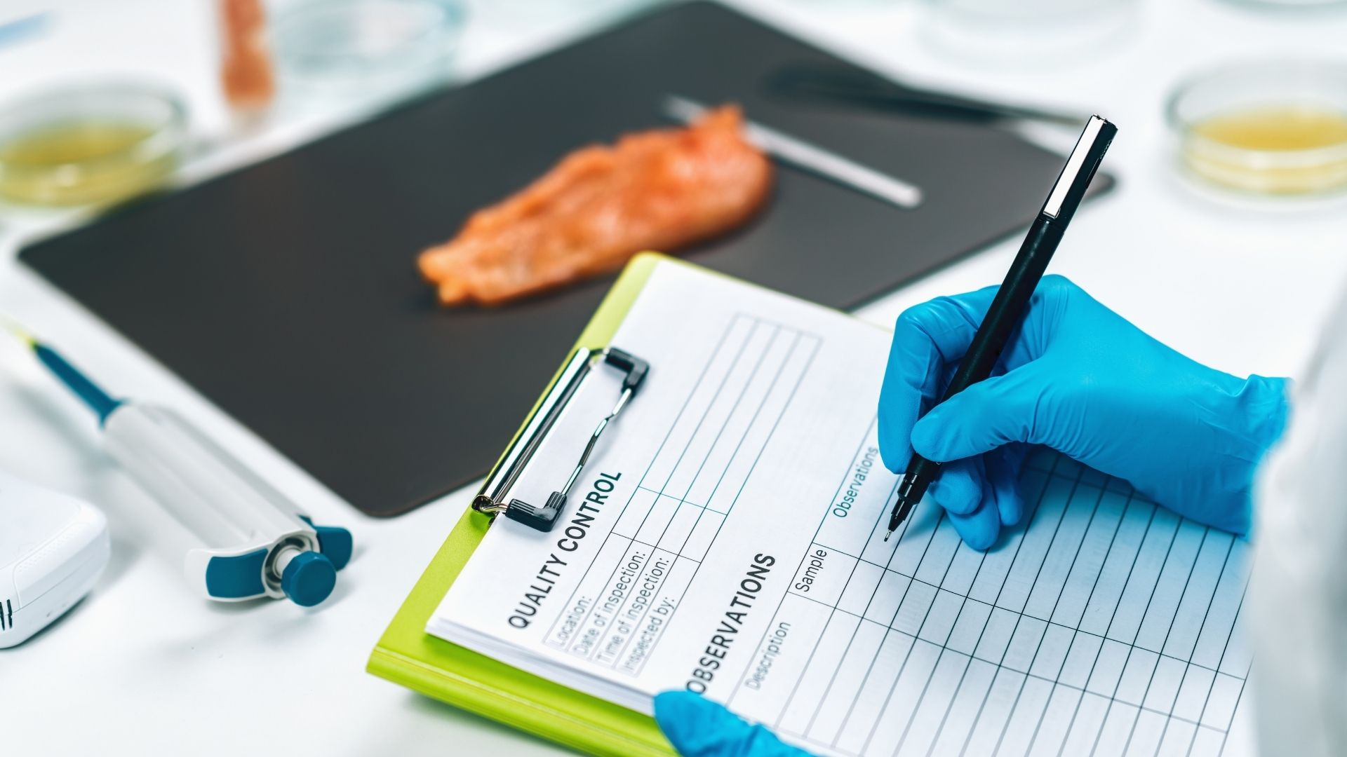 Profissional realizando controle de qualidade em alimentos com ficha de inspeção e luvas em laboratório.
