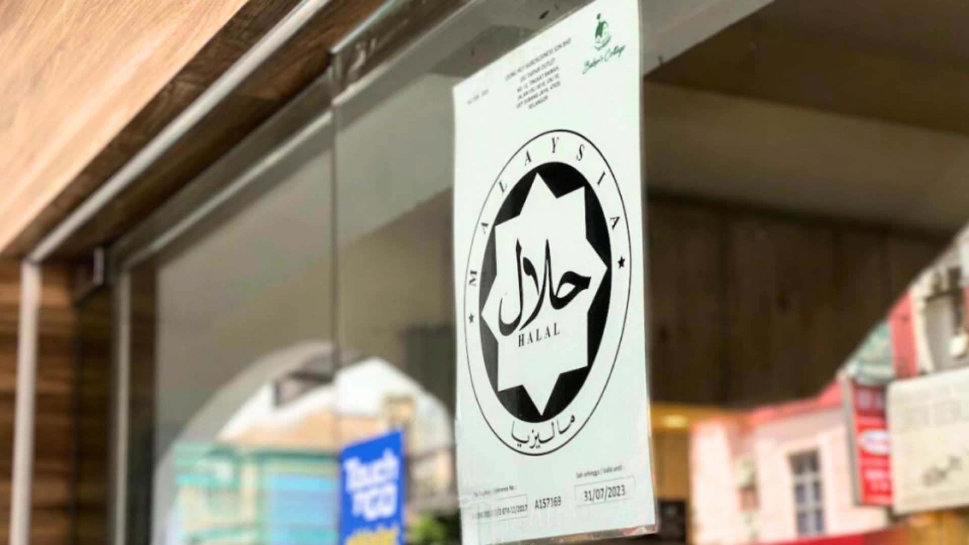 Certificado oficial Halal do Jakim com seu logotipo distintivo em forma de estrela exibido na entrada de um estabelecimento comercial, demonstrando conformidade com as normas de certificação Halal da Malásia.
