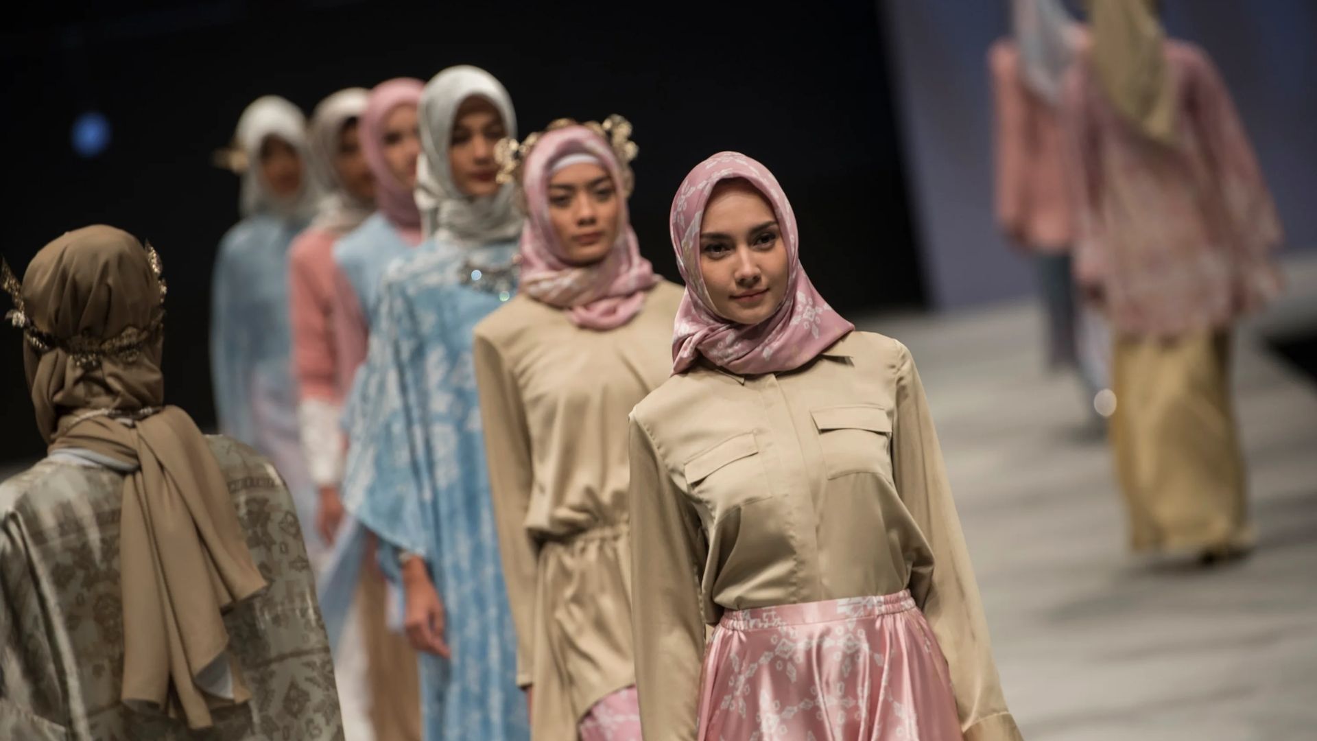 Modelos desfilando roupas de moda modesta em tons pastel, representando a sofisticação e inovação do segmento Halal.